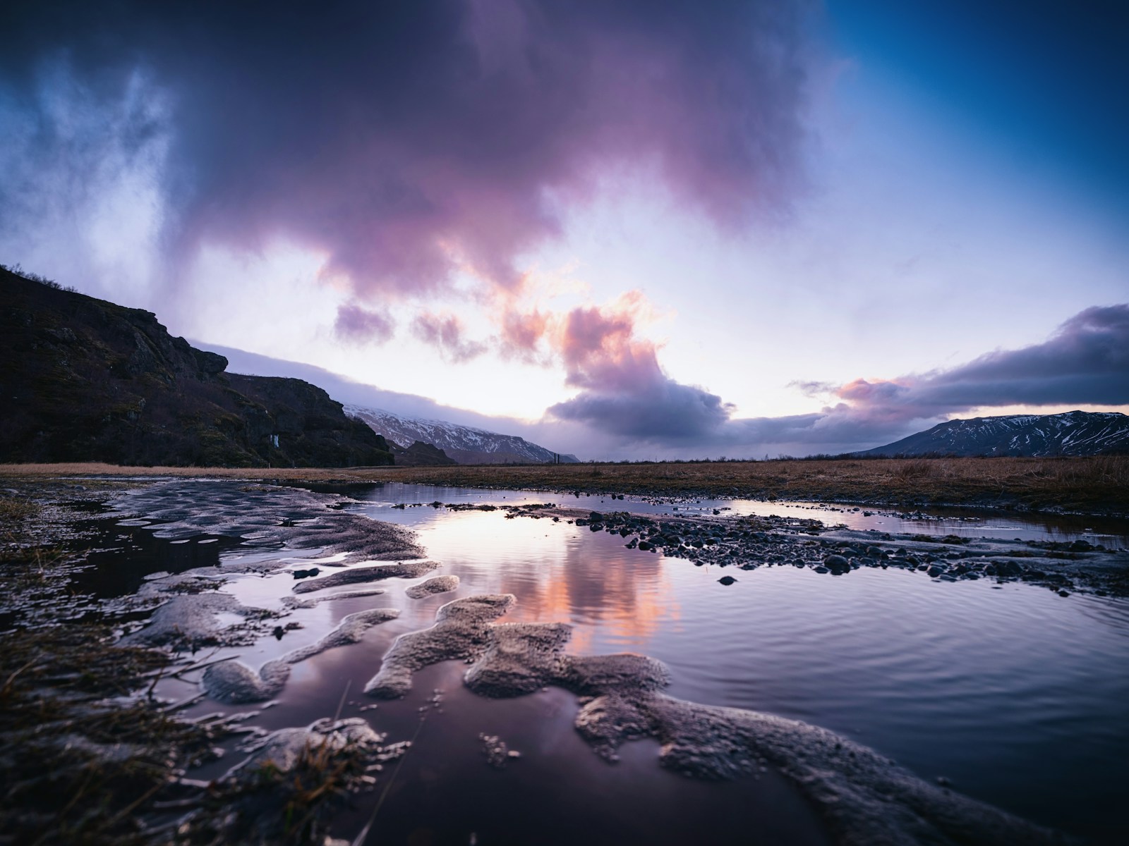 A body of water surrounded by mountains and clouds